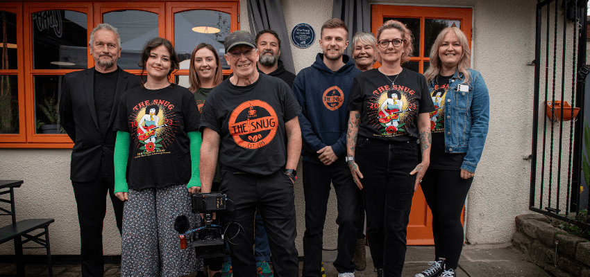 a group of people standing in front of The Snug Coffee House in Atherton