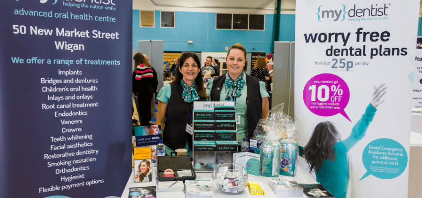 two individuals standing next to a table at a business expo