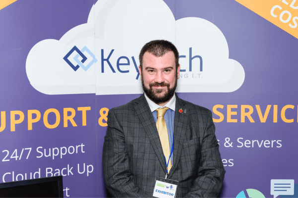 a person in a suit and tie standing in front of a cloud computing sign