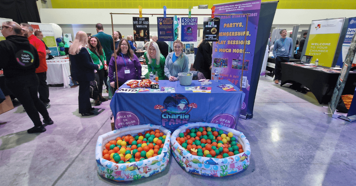 people standing around a table with colourful balls in a ball pool