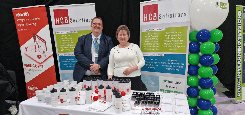 Two people standing next to a table with balloons at Wigan Business Expo